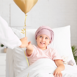 Young child with head scarf smiling and accepting a gold balloon