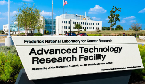 Outdoor view of building and sign reading: Frederick National Laboratory for Cancer Research Advanced Technology Research Facility - Operated by Leidos Biomedical Research, Inc., for the National Cancer Institute. Department of Health and Human Services - National Institutes of Health.