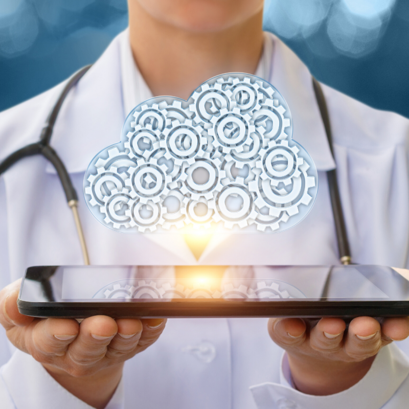 Doctor wearing stethoscope holding tablet with graphic of a cloud above, depicting cloud computing.