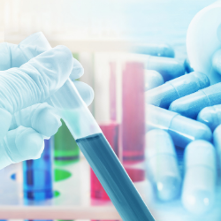 Image of gloved hand holding a test tube filled with blue liquid; in the background are pills, making the association between research and drug development.