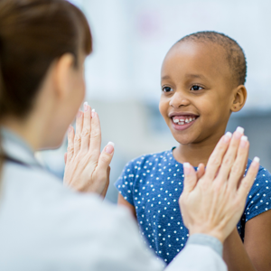 Picture of a childhood cancer patient high-fiving a physician.