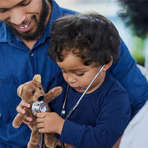 Childhood cancer patient trying to listen to the heartbeat of their teddy bear with a stethoscope.