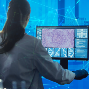Person in lab coat with hair pulled back looks at screen with cancer data science theme