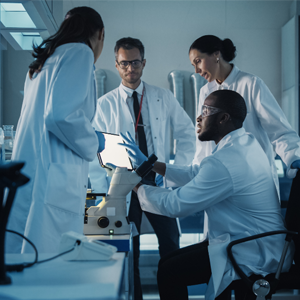 Scientists in lab coats working together around a screen