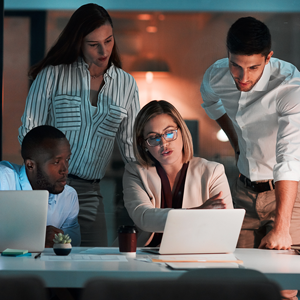 four people examining a laptop