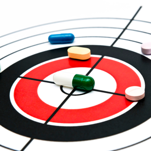 Target shows one medication capsule in the bull’s eye, with four more tablets in the outside rings of the target. Illustrates the difficulty in finding the precise medication for treating diseases like cancer. 