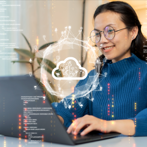 Woman wearing a blue sweater and round glasses sitting at a laptop. Cloud computing icon and data elements overlay the back of the screen to represent to show she's uploading and transferring data from computer to cloud.