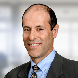 Professional headshot of Dr. Gordon Harris. Situated against a neutral backdrop, Gordon is dressed in a suit and tie and he's smiling at the camera.