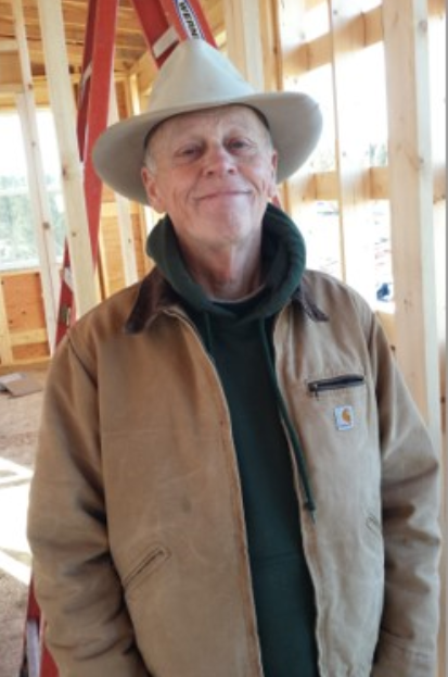 Dr. Ed Helton wearing a hat and smiling in a room under construction.