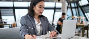 Image of professional taking notes by a laptop